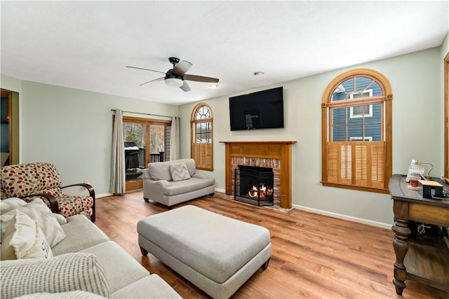 living room with hardwood / wood-style floors, ceiling fan, and a brick fireplace