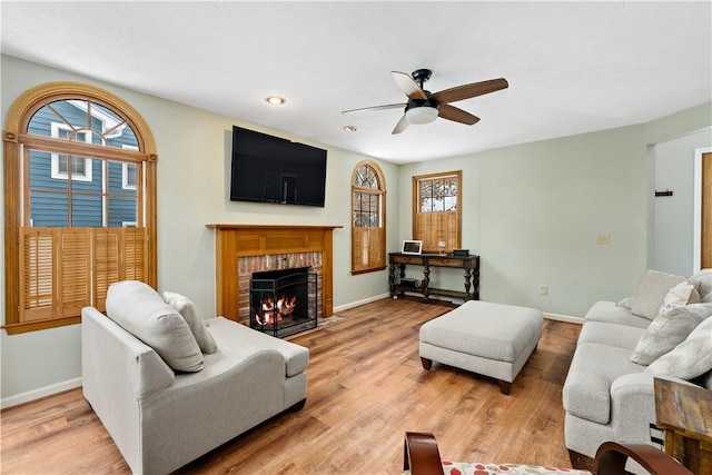 living room featuring light wood-type flooring, a brick fireplace, and ceiling fan