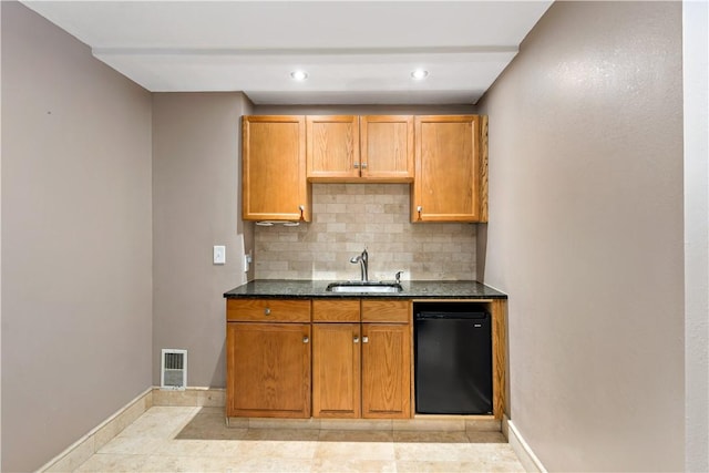 kitchen with decorative backsplash, black dishwasher, dark stone countertops, and sink