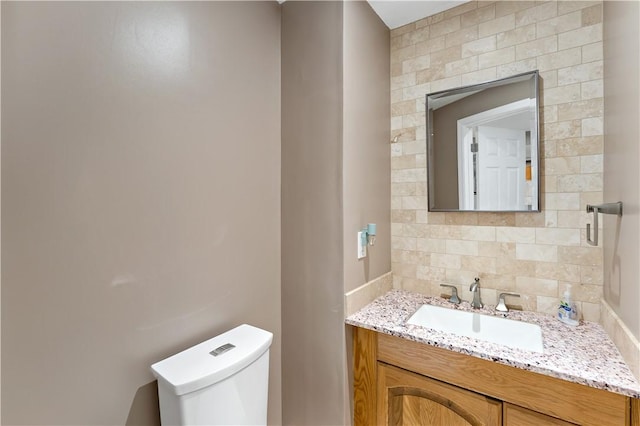 bathroom with vanity, toilet, and backsplash