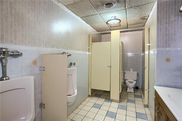 bathroom featuring tile walls, toilet, vanity, and a drop ceiling