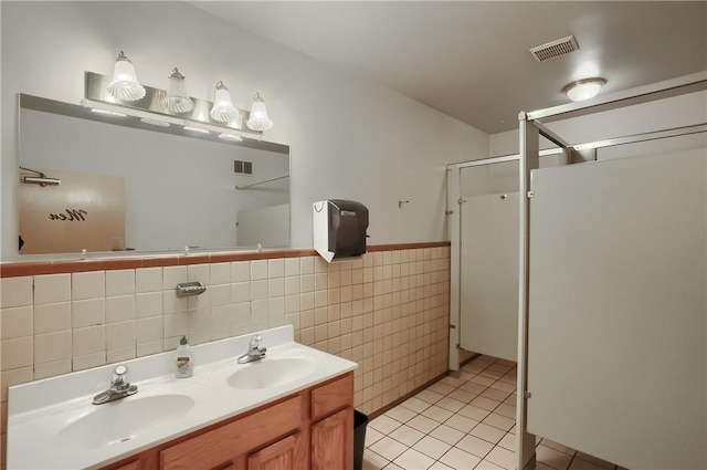 bathroom with a shower with door, vanity, tile walls, and tile patterned floors