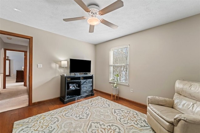 living area with ceiling fan, hardwood / wood-style floors, and a textured ceiling