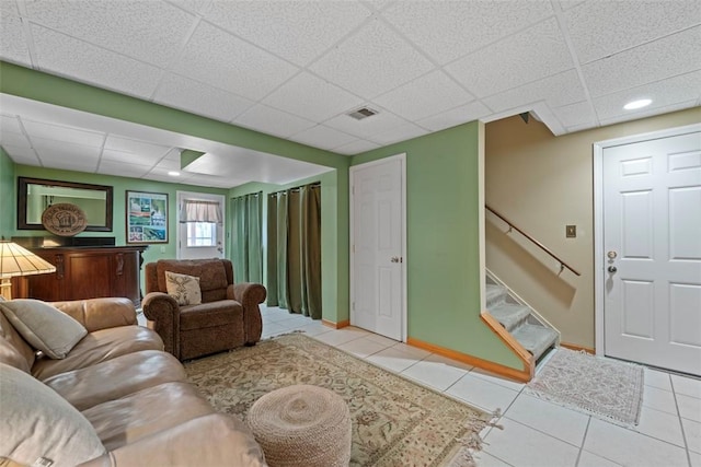 living room featuring a drop ceiling and light tile patterned floors