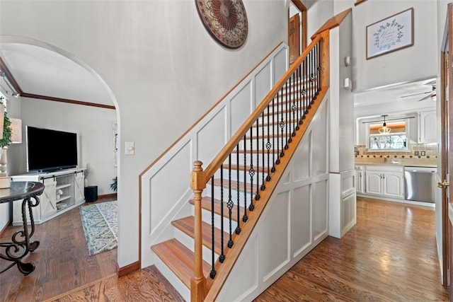 staircase with hardwood / wood-style floors, a healthy amount of sunlight, and crown molding