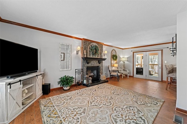 living room featuring a tiled fireplace, crown molding, and hardwood / wood-style floors