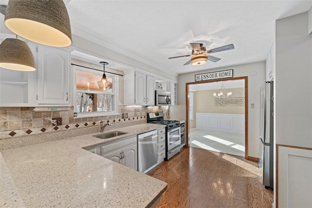 kitchen featuring light stone countertops, sink, backsplash, white cabinets, and appliances with stainless steel finishes