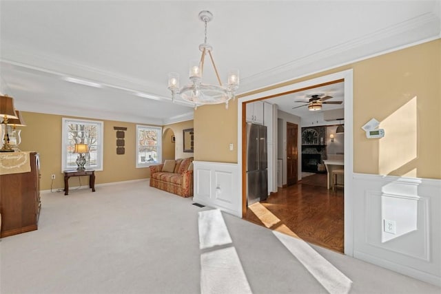 interior space featuring ceiling fan with notable chandelier, wood-type flooring, ornamental molding, and a fireplace