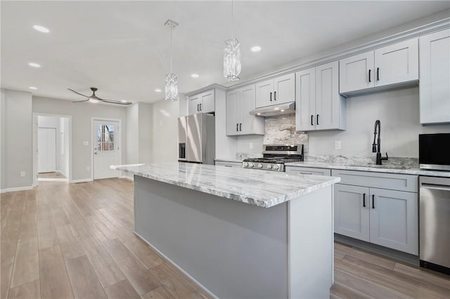 kitchen featuring sink, hanging light fixtures, ceiling fan, light wood-type flooring, and stainless steel appliances