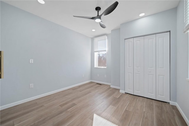 unfurnished bedroom with ceiling fan, light wood-type flooring, and a closet