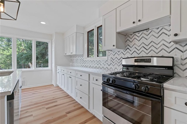 kitchen featuring light stone countertops, decorative backsplash, light wood-type flooring, stainless steel appliances, and white cabinetry