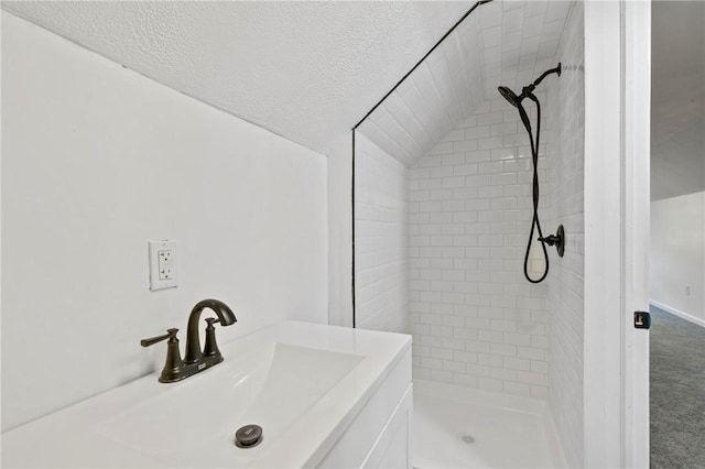 bathroom with vanity, a tile shower, and a textured ceiling