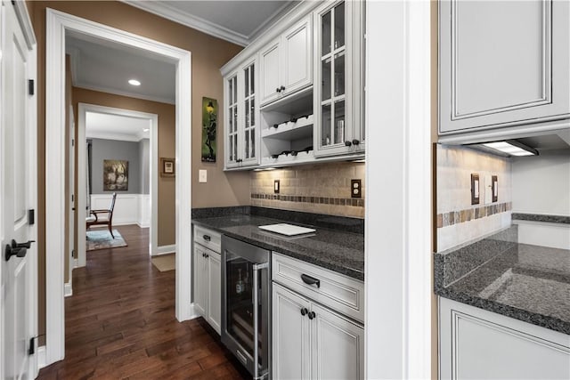 kitchen featuring dark hardwood / wood-style flooring, tasteful backsplash, ornamental molding, beverage cooler, and white cabinets