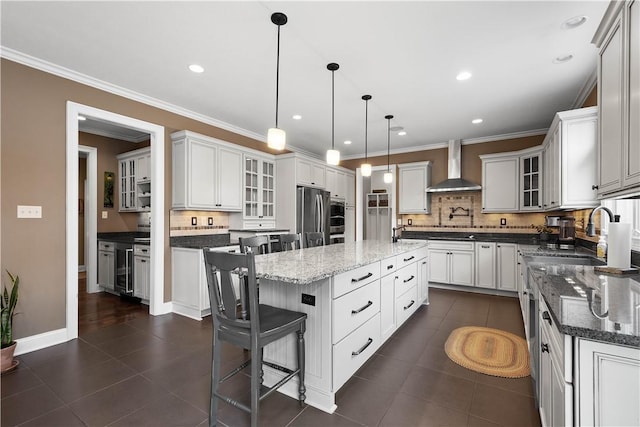 kitchen with white cabinetry, a center island, wall chimney range hood, backsplash, and stainless steel fridge