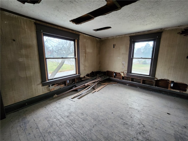 unfurnished room with hardwood / wood-style floors, a textured ceiling, and wooden walls