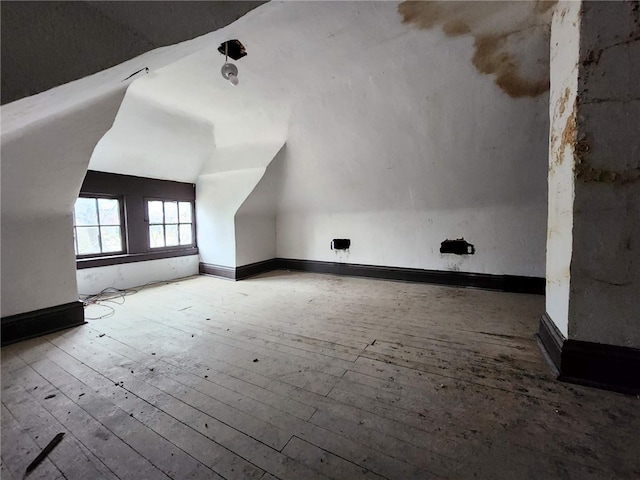 bonus room with light wood-type flooring and vaulted ceiling