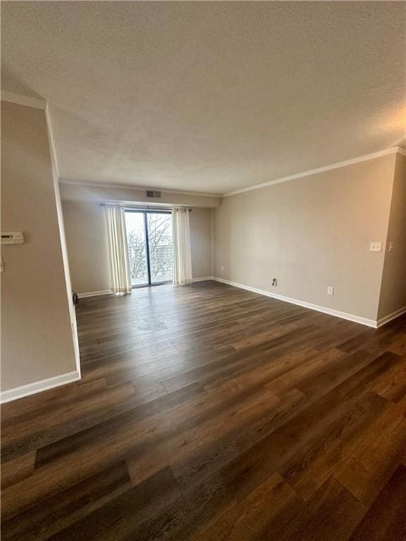 empty room featuring a textured ceiling, crown molding, and dark wood-type flooring