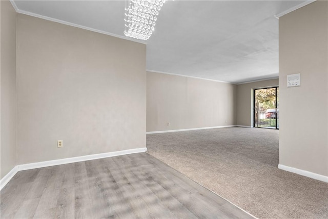 carpeted spare room with an inviting chandelier and ornamental molding