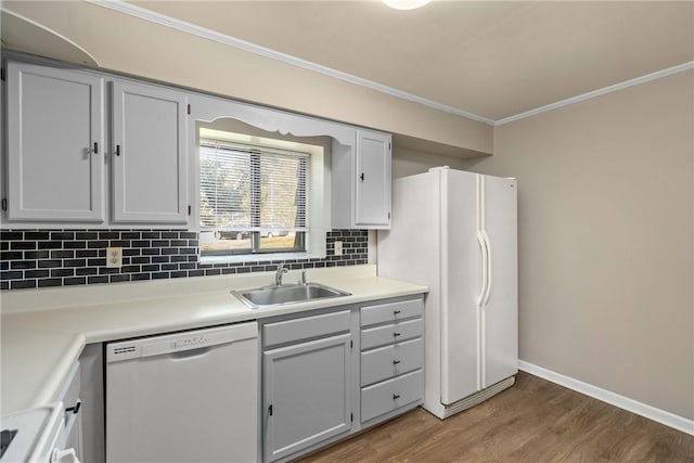 kitchen featuring white appliances, backsplash, crown molding, sink, and wood-type flooring