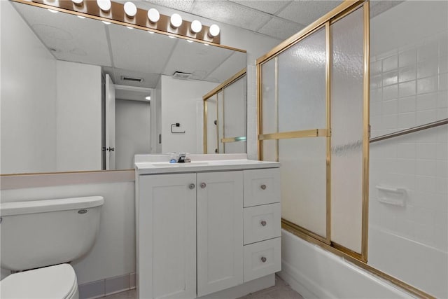 full bathroom featuring a paneled ceiling, vanity, bath / shower combo with glass door, and toilet