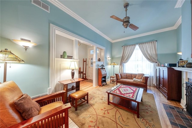 sitting room with ceiling fan, light hardwood / wood-style floors, crown molding, and a tiled fireplace