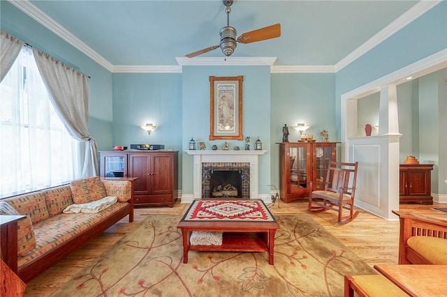 living area featuring a fireplace, light wood-type flooring, plenty of natural light, and ornamental molding