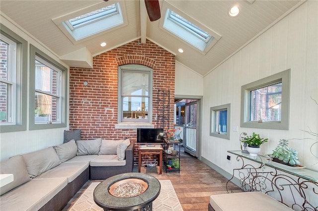 living room with light wood-type flooring, ornamental molding, brick wall, and vaulted ceiling