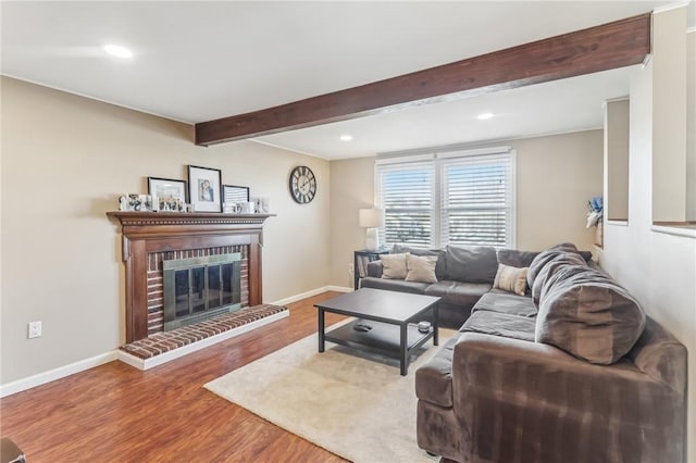 living room with hardwood / wood-style flooring, beam ceiling, and a fireplace