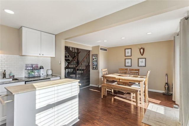 kitchen with backsplash, white cabinets, sink, stainless steel dishwasher, and dark hardwood / wood-style flooring