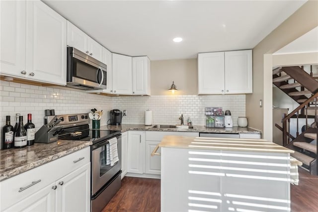 kitchen featuring sink, a center island, stainless steel appliances, backsplash, and white cabinets