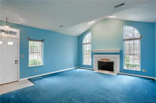 unfurnished living room featuring carpet flooring, lofted ceiling, a textured ceiling, and a tile fireplace