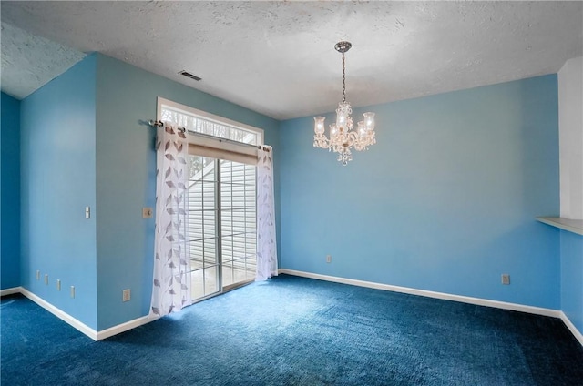 carpeted empty room featuring a textured ceiling and a chandelier