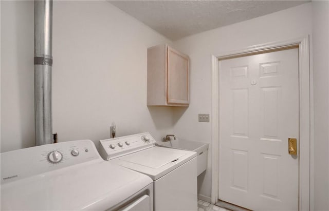 laundry area with washer and dryer, a textured ceiling, and cabinets