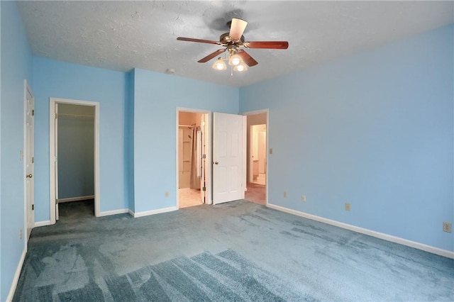 unfurnished bedroom with a walk in closet, carpet floors, ceiling fan, and connected bathroom