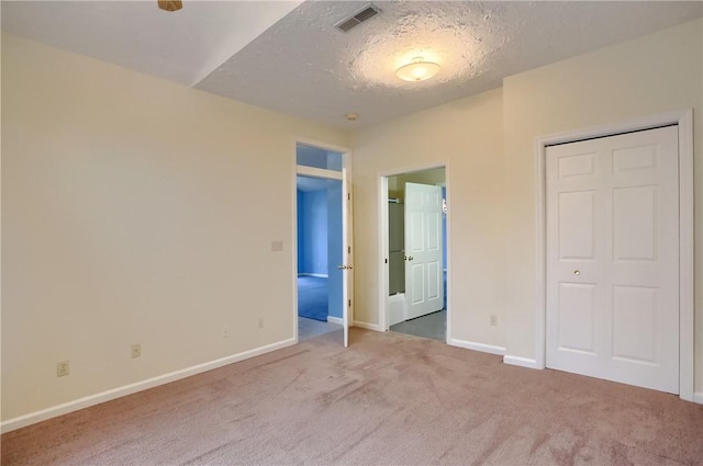 unfurnished bedroom with carpet flooring, a textured ceiling, and lofted ceiling