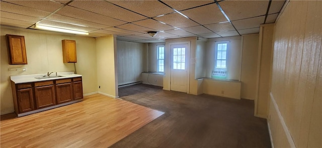 interior space featuring baseboard heating, sink, a drop ceiling, and light wood-type flooring