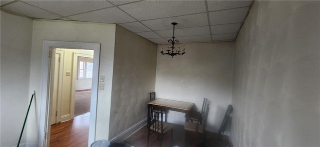 unfurnished dining area with dark hardwood / wood-style flooring, a paneled ceiling, and an inviting chandelier