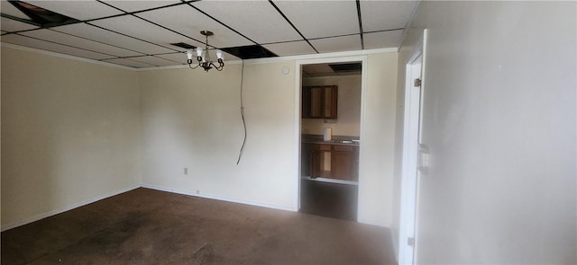 unfurnished room with a drop ceiling, carpet, and a chandelier