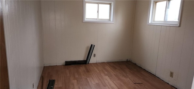 unfurnished room featuring a wealth of natural light, light hardwood / wood-style floors, and wooden walls