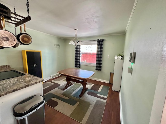 dining area with an inviting chandelier, crown molding, and dark wood-type flooring