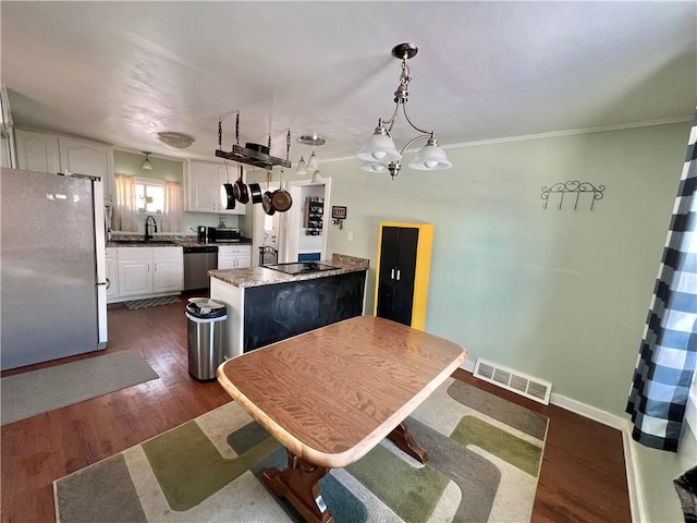 kitchen featuring decorative light fixtures, a kitchen island, white cabinetry, and appliances with stainless steel finishes