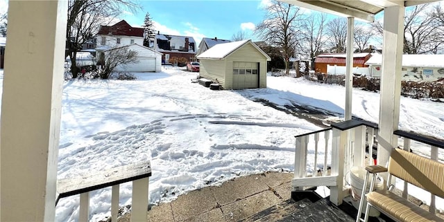 yard layered in snow with an outdoor structure and a garage