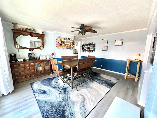 dining room featuring ceiling fan, crown molding, wood-type flooring, and a textured ceiling