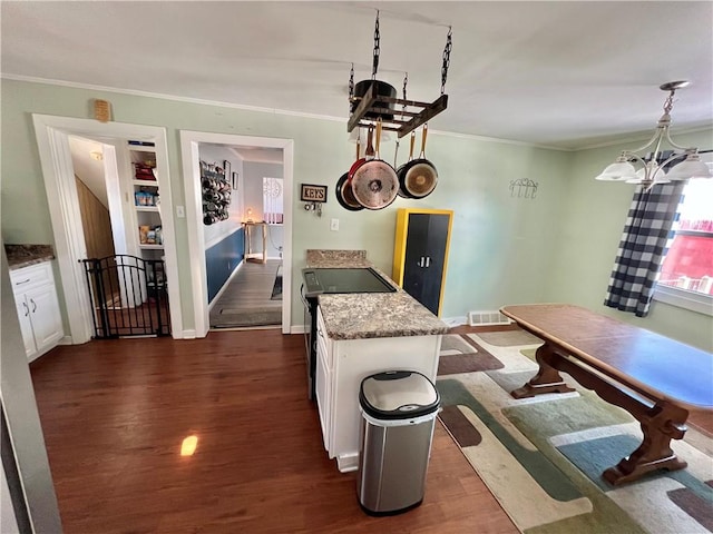 dining area featuring dark hardwood / wood-style flooring, crown molding, and a chandelier