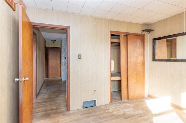 unfurnished bedroom featuring wood walls, a closet, and light hardwood / wood-style flooring