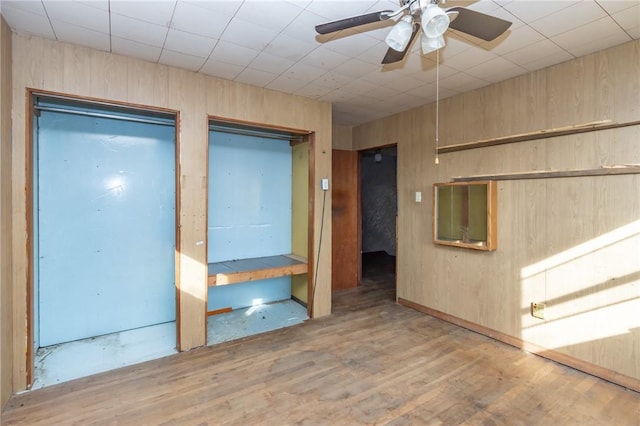 empty room featuring wood walls, ceiling fan, and light hardwood / wood-style floors