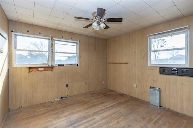 unfurnished room featuring wood walls, ceiling fan, and light hardwood / wood-style floors