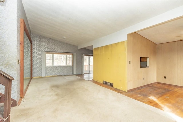 unfurnished room with ceiling fan, wood walls, wood-type flooring, and lofted ceiling