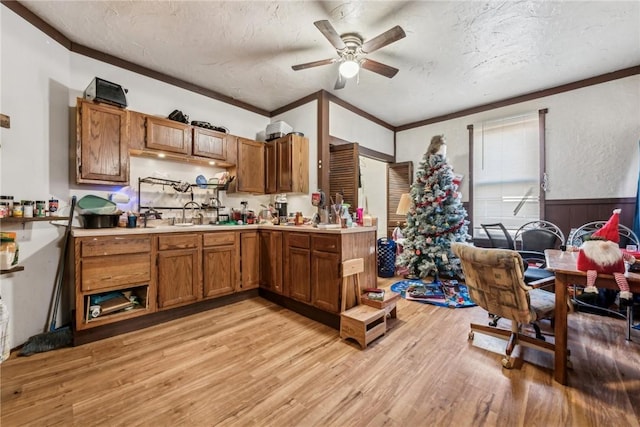 kitchen featuring ceiling fan, sink, a textured ceiling, and light wood-type flooring