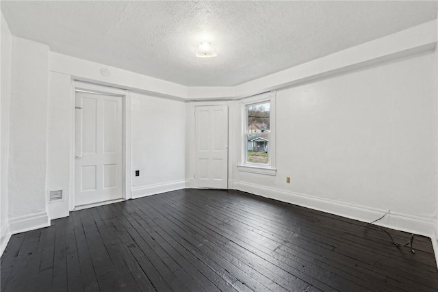 empty room with dark hardwood / wood-style flooring and a textured ceiling